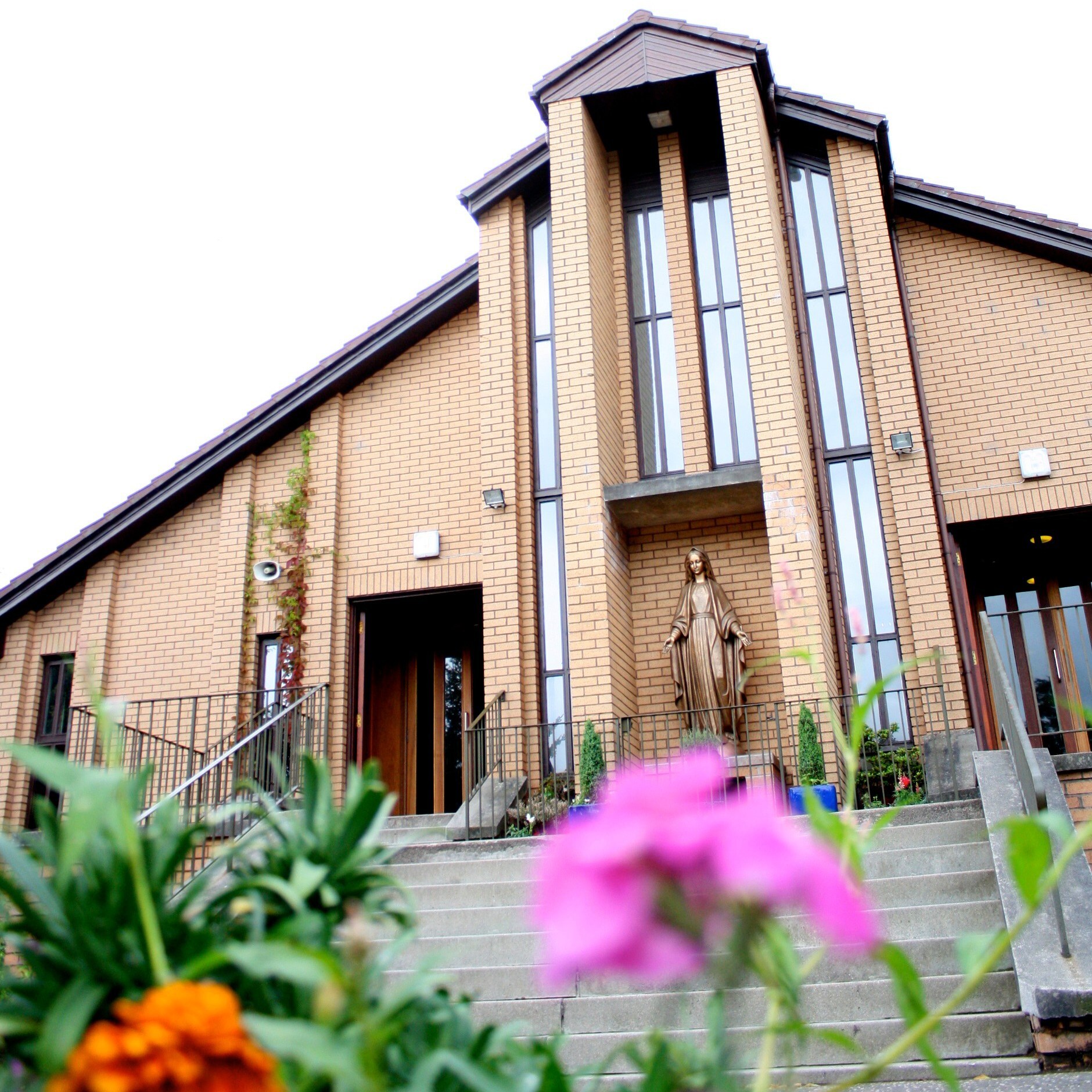 view of the church from below with pink and orange flowers in the foreground